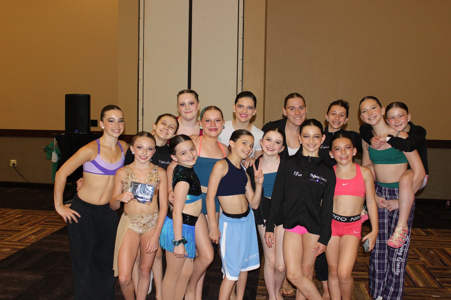 A group of dancers gathered together in costumes and studio jackets.